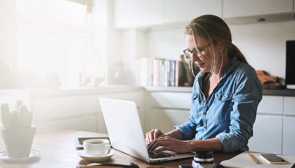 Image of a woman sitting on a table in front of a laptop